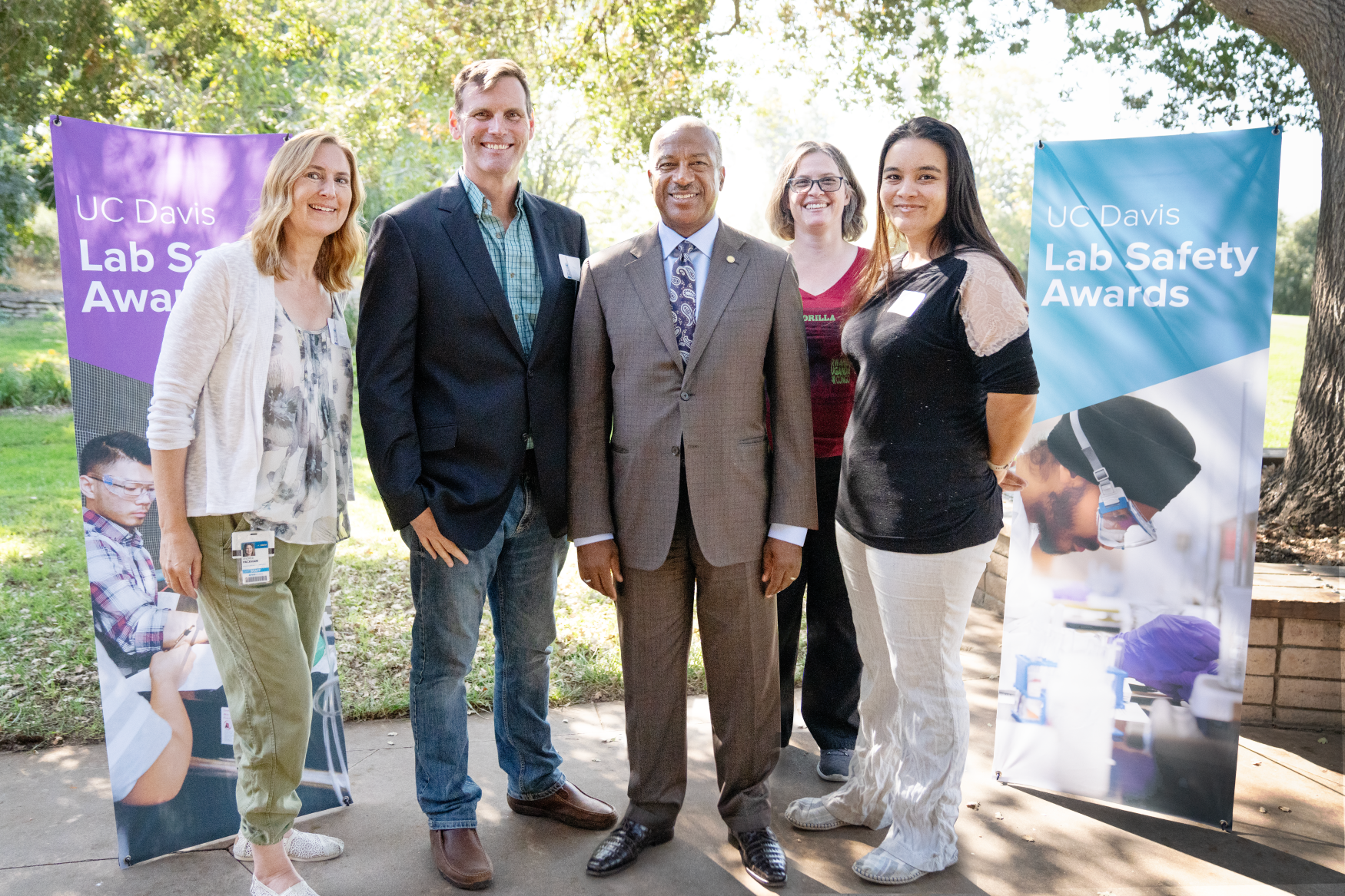Five people stand outside smiling at the camera.